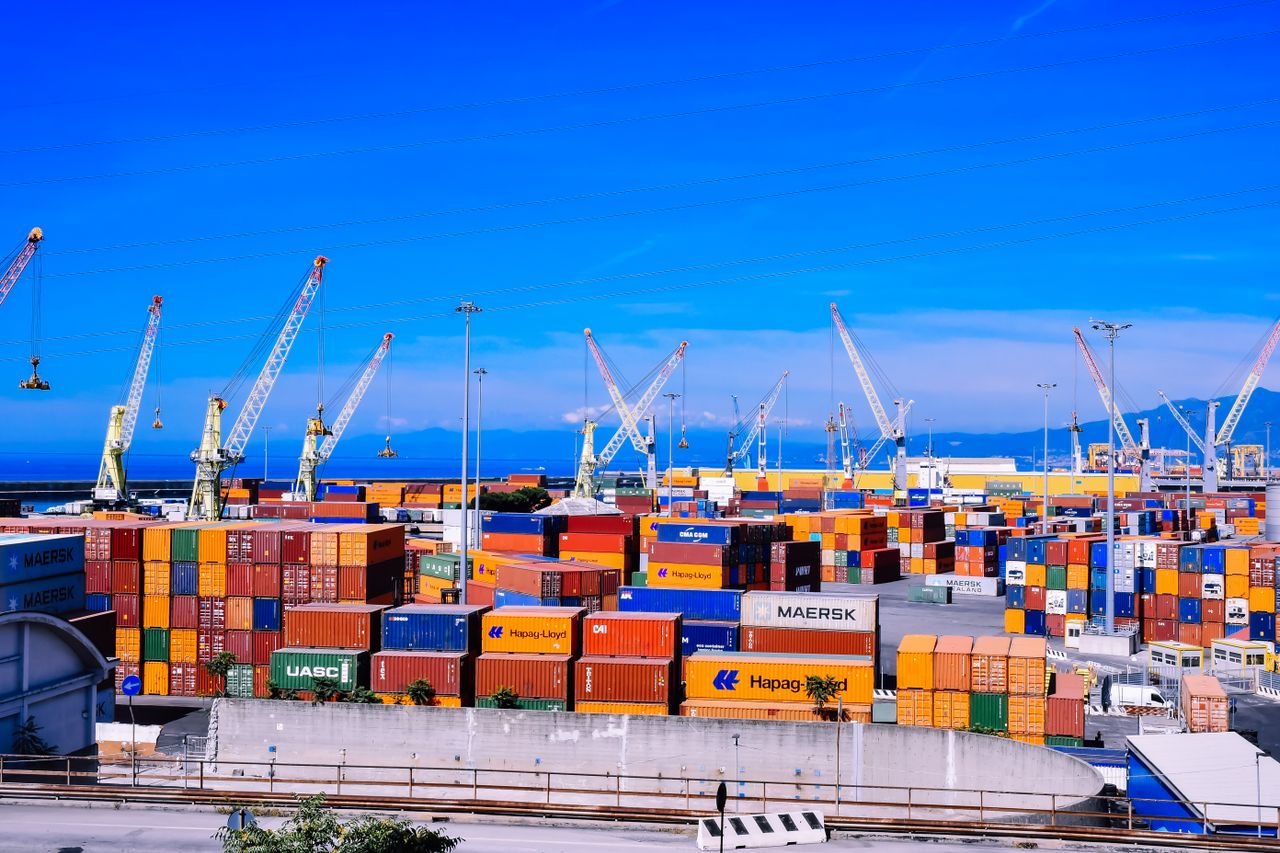 The Art of Drawing Readers In: Your attractive post title goes here A bustling shipping port with colorful stacked containers and numerous cranes under a clear blue sky.