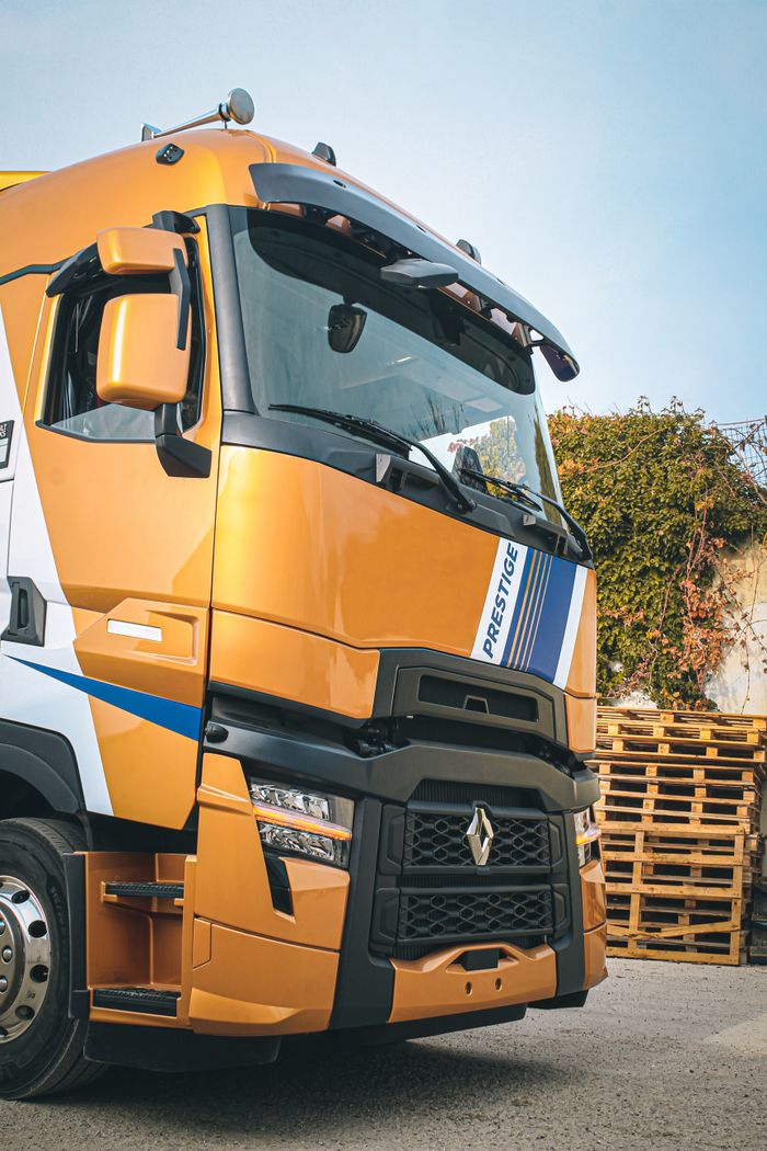 A vibrant golden truck parked outdoors near wooden pallets on a sunny day.