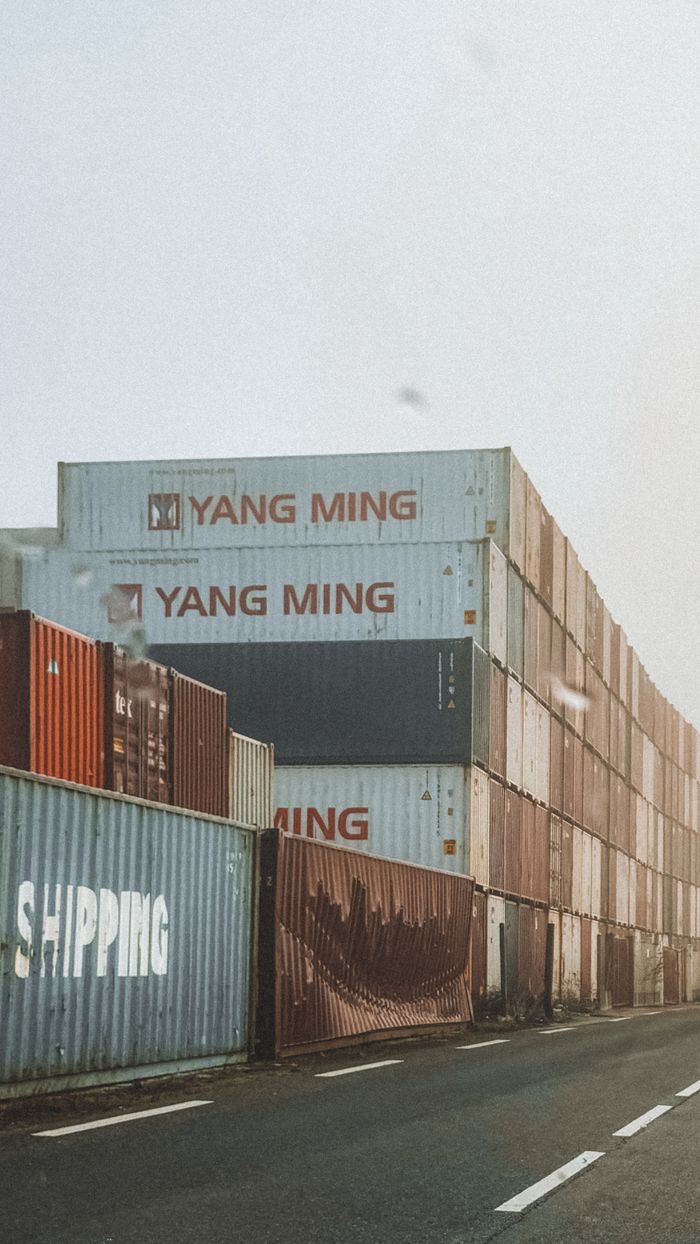 services-10 Rows of Yang Ming shipping containers stacked at port under hazy sky.