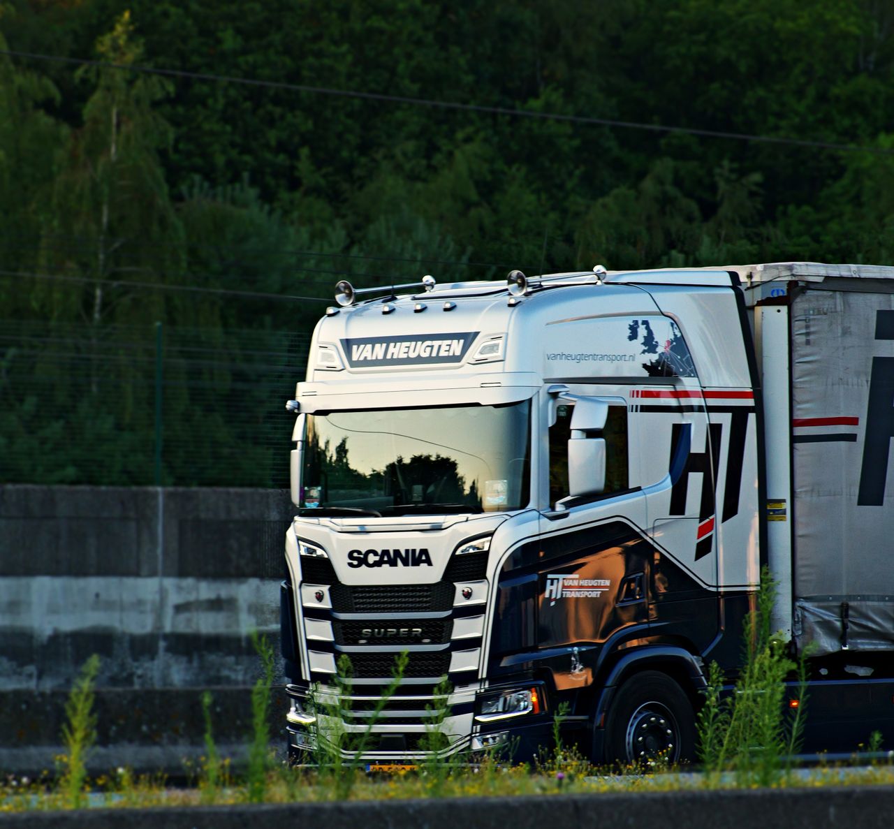 A Scania truck from Van Heugten Transport driving on an outdoor highway.